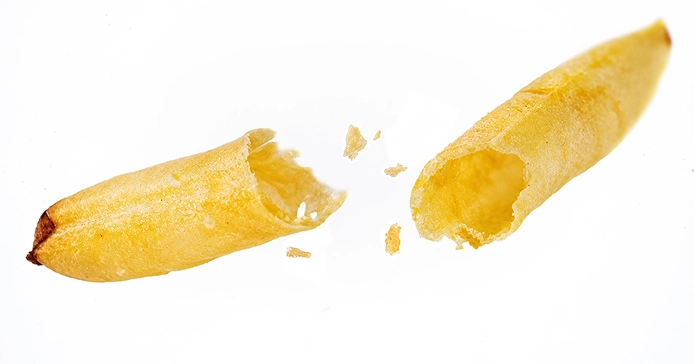 A crisp potato stick snapped in two, showing its hollow, airy inside